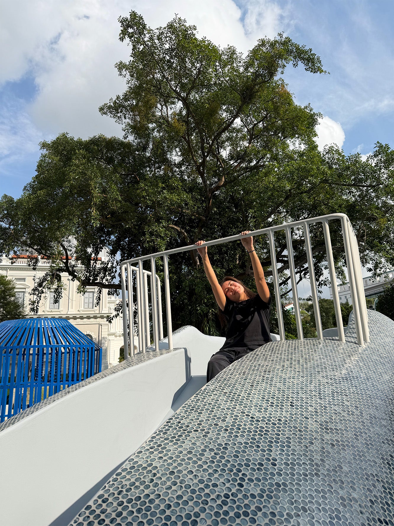 A lady sitting atop Whale of a Tale playground at the National Museum Singapore, the first intergenerational playground.