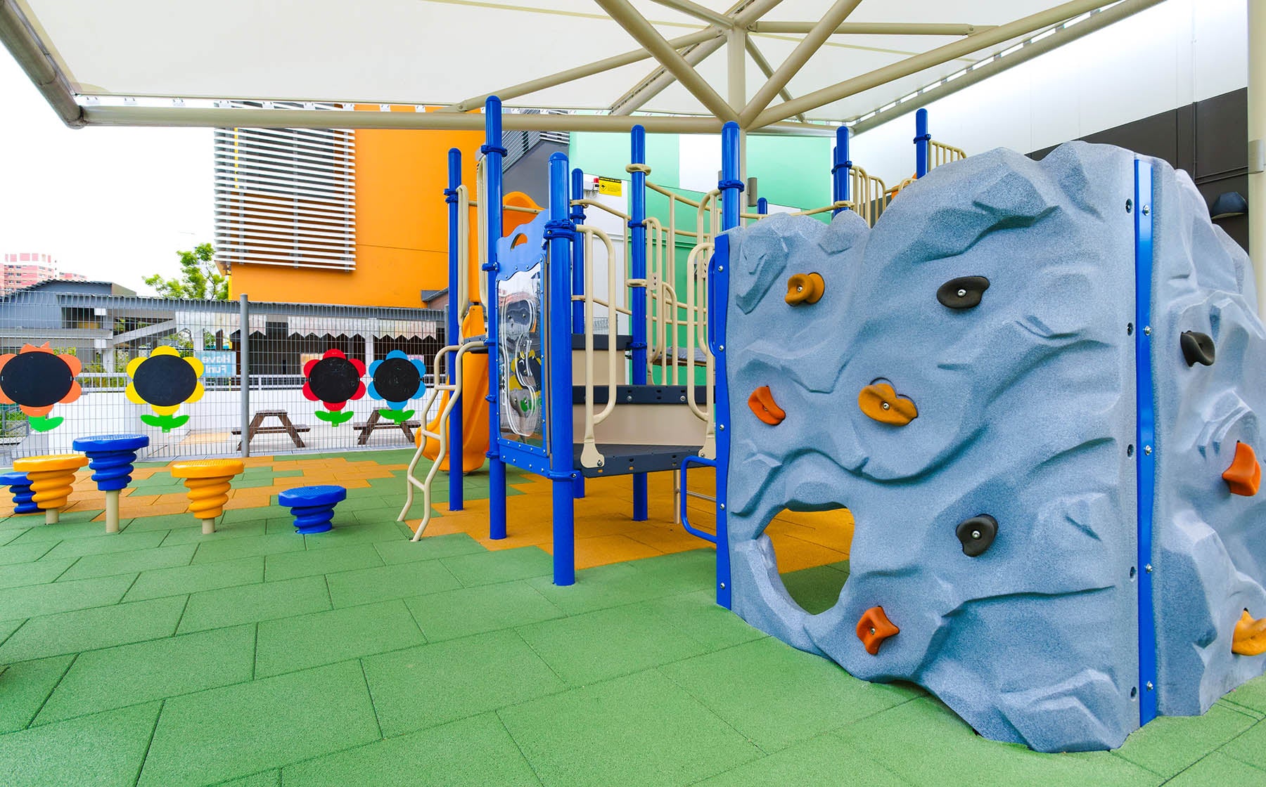 The shaded Playworld playground features a Corner Rock for climbing, along with hopping and sliding play activities.