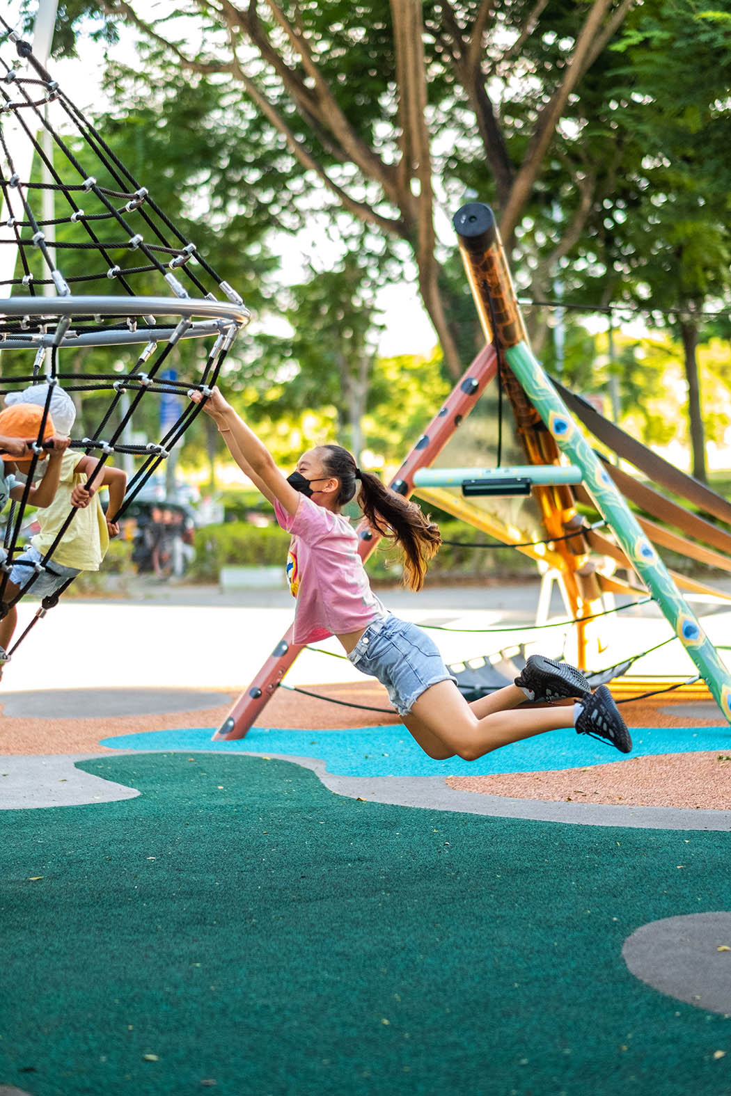 Girl enjoying the Playworld diamond cone spinner, holding onto the structure while spinning.