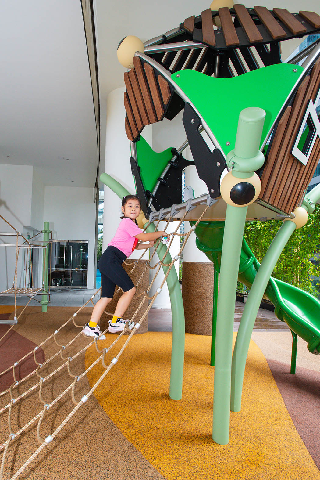 One Shenton playground featuring Berliner Greenville with a rope net and slide for active outdoor play.