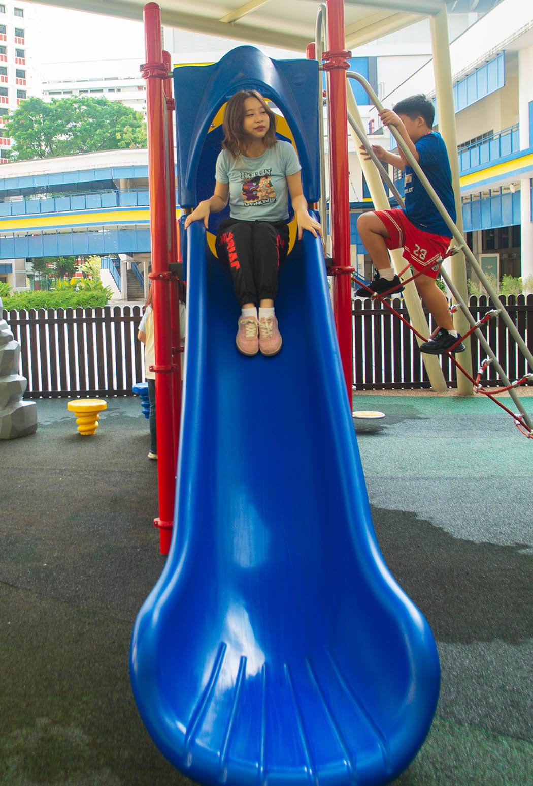 Girl happily sliding down the Playworld playground slide, filled with enjoyment.