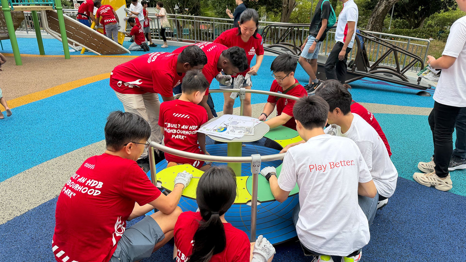 Pasir Ris residents assemble the Merry-Go-Round, showing teamwork while securing seat bolts for safe play.