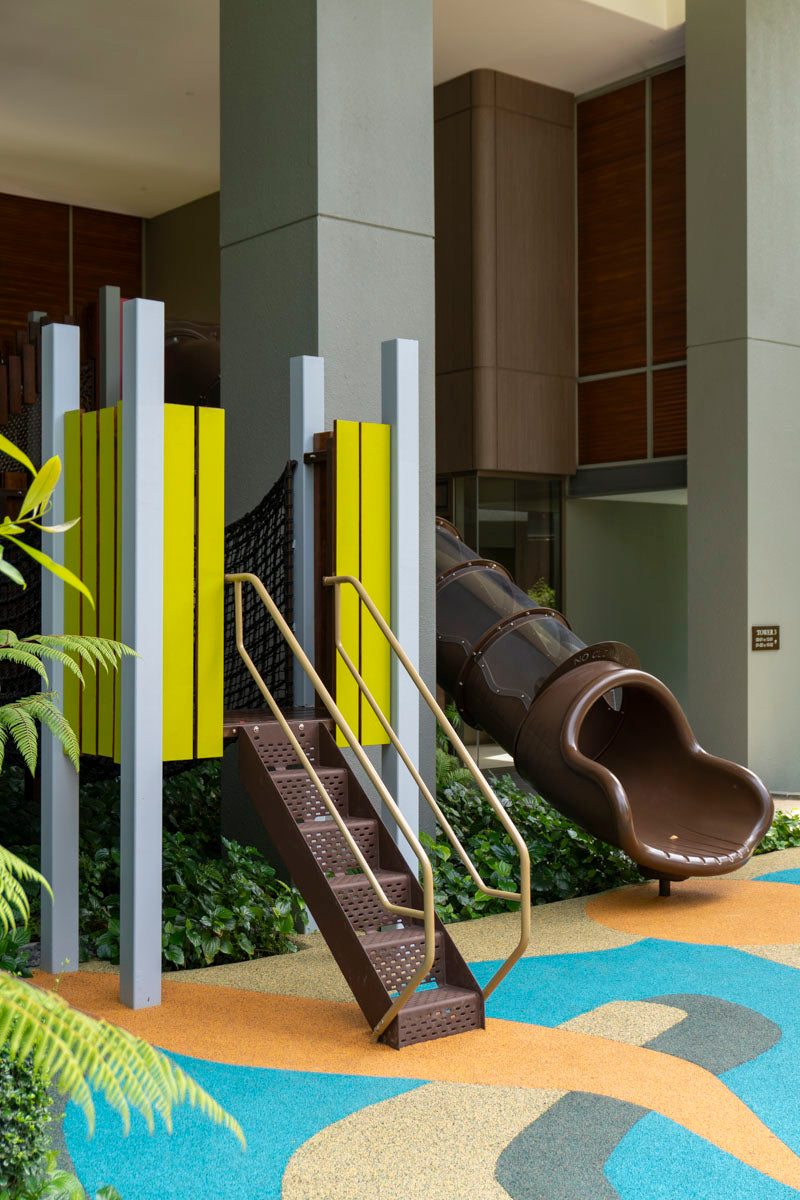 Colorful playground with a tall slide, surrounded by soft ground and open space, designed for kids' play and fun