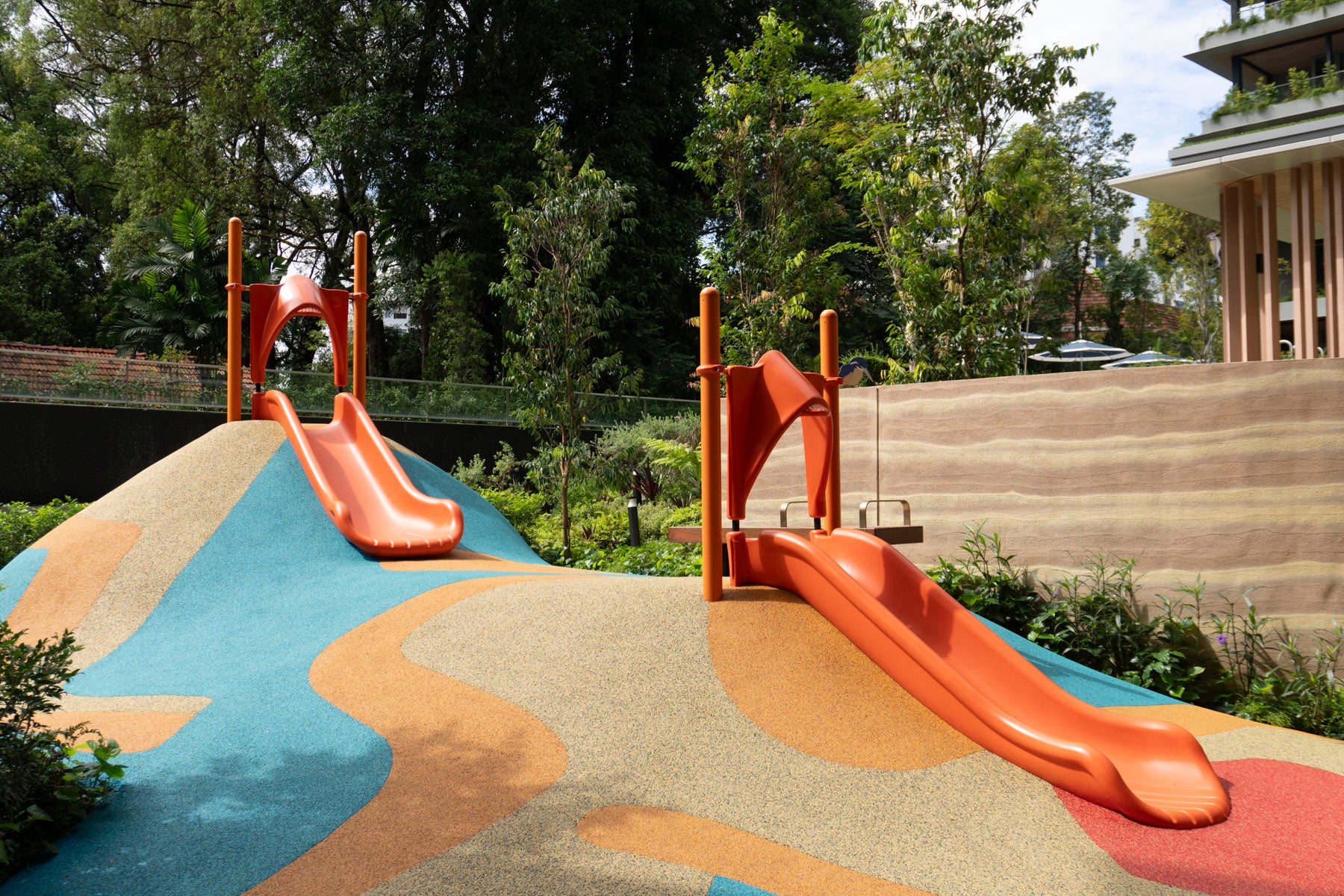 Orange playground with a two slide, surrounded by soft ground specially designed for kids' safe play and fun