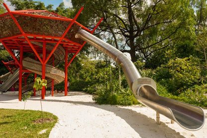 A playground with multiple play areas, featuring a large long slide and space for kids to play and explore.