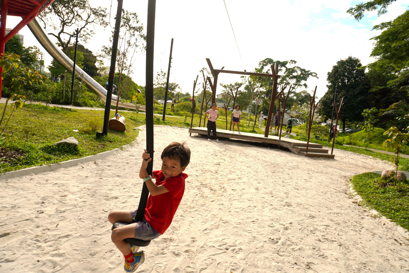 A smiling child glides on a zipline in a vibrant playground, surrounded by greenery, showcasing joy and adventure.