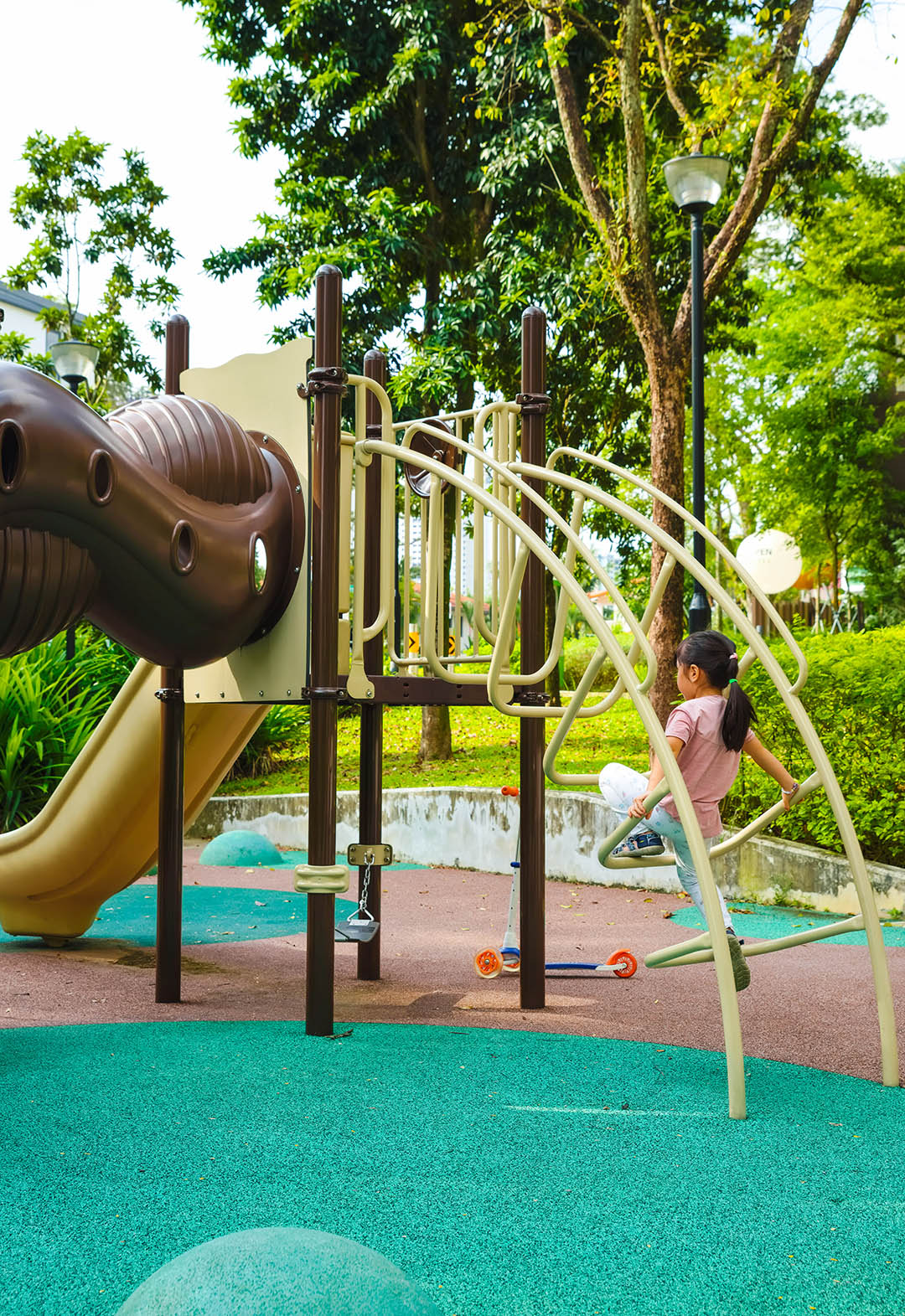 A playground with a girl climbing up the stairs, focused and enjoying the challenge of reaching the top.