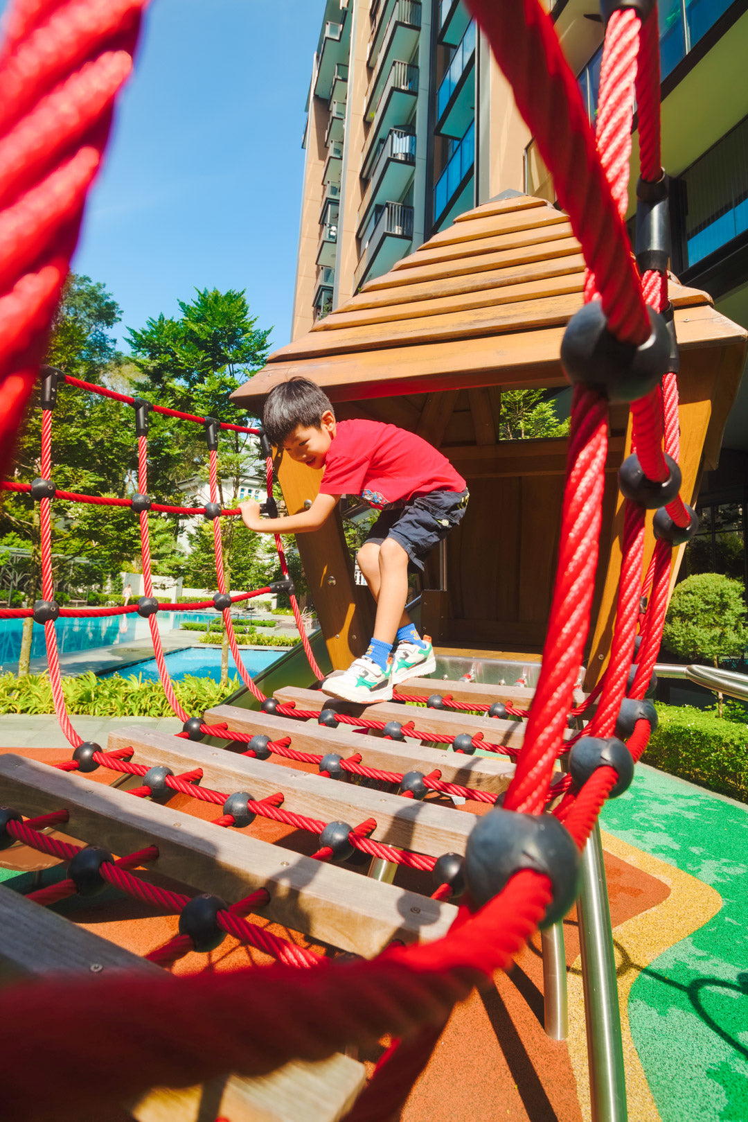 A boy carefully crossing a rope bridge, balancing as he navigates the playground’s adventurous obstacle.