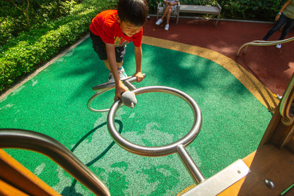  A boy climbing up curved metal poles to reach the playground's top, taking on an exciting and adventurous challenge.