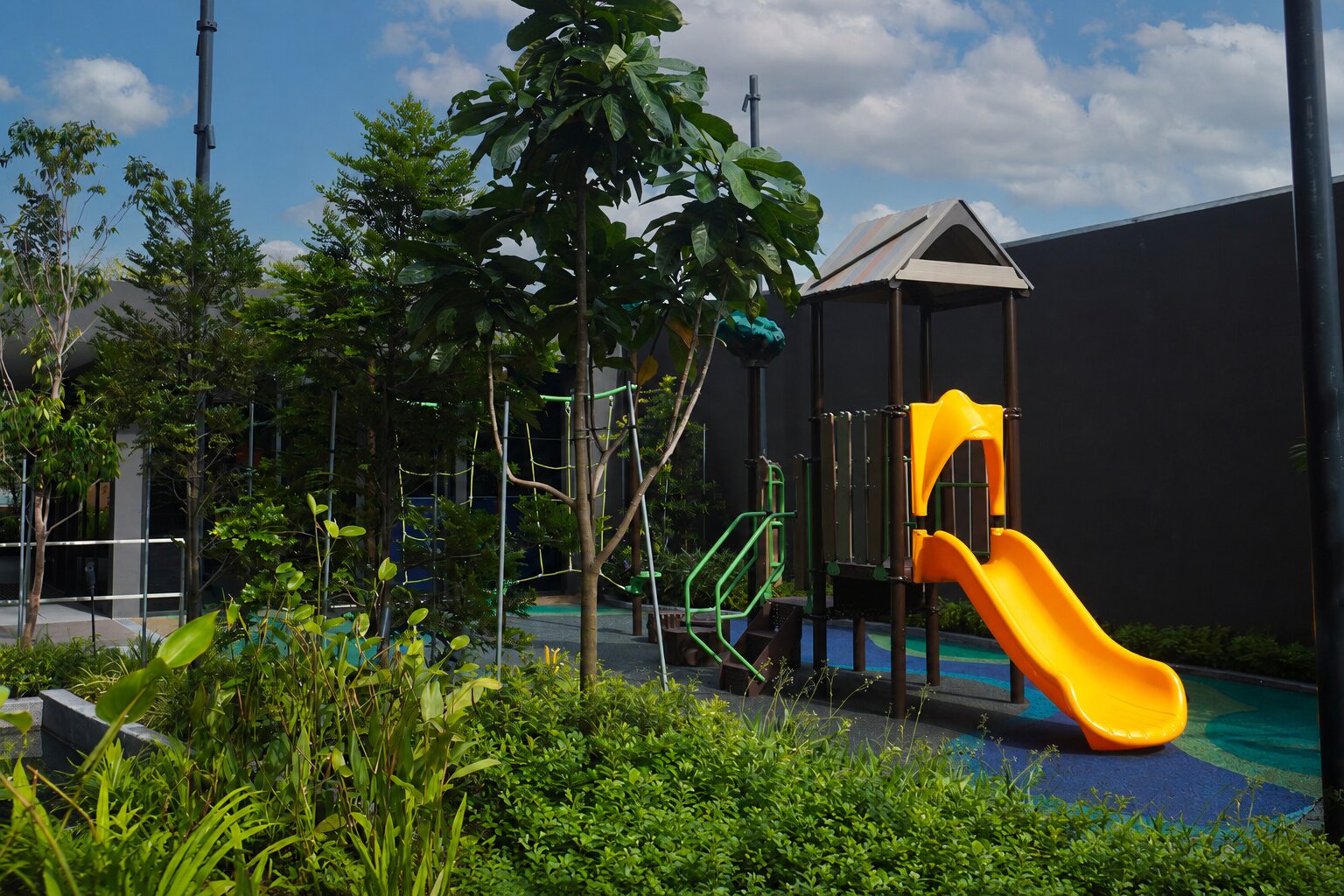 Lentor Modern treehouse-design playground with elevated platform, stair access and a yellow slide for active play.