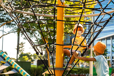 Brothers enjoying the Playworld Diamond Cone Spinner, with one pushing the structure for added spinning fun.