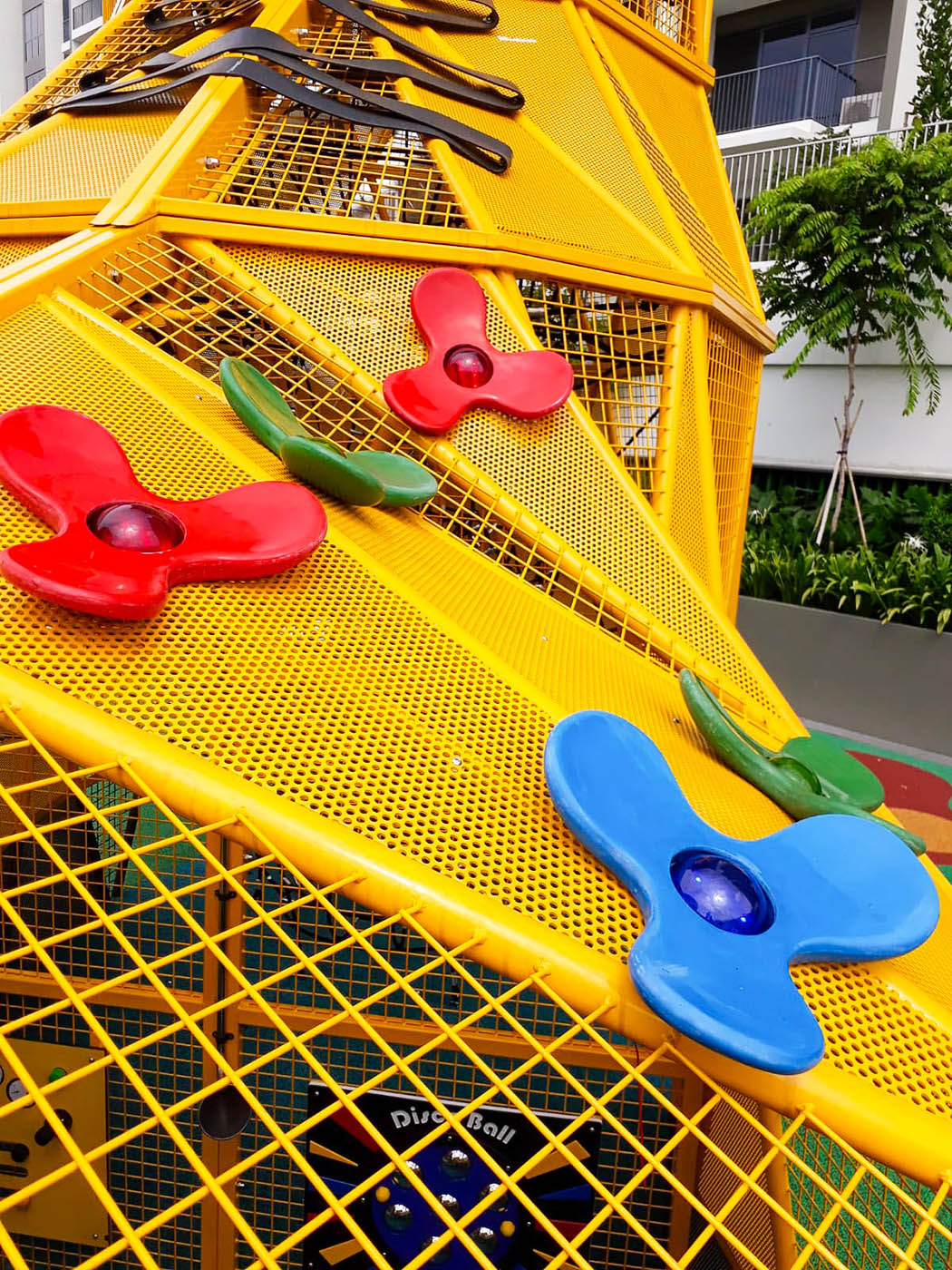 Vibrant flower-shaped climbing grips on a custom shoe-shaped playground, designed for creative and engaging play.