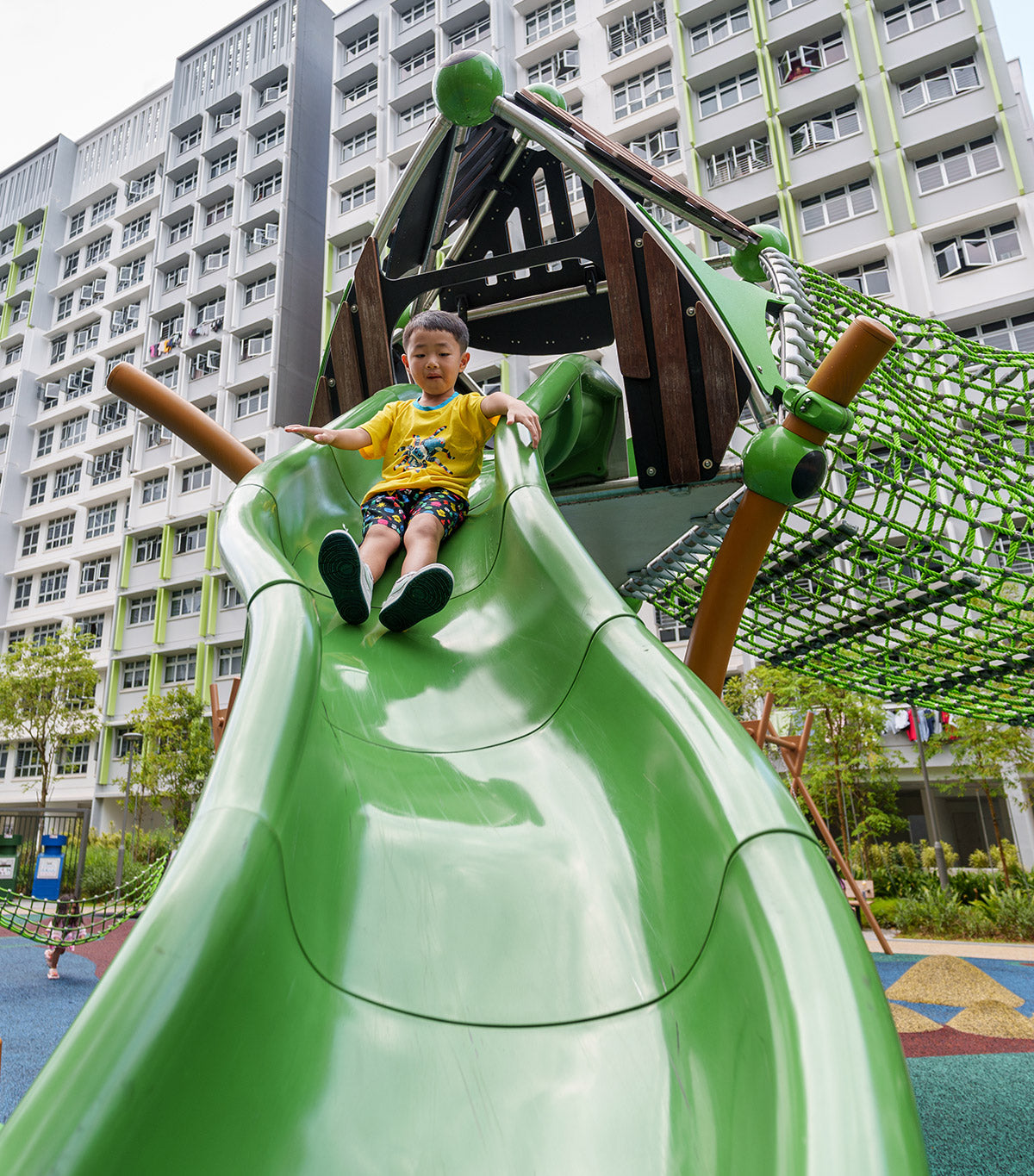 Boy sliding down a Berliner Treehouse at Yishun Melody Spring playground, enjoying a fun and active outdoor experience.