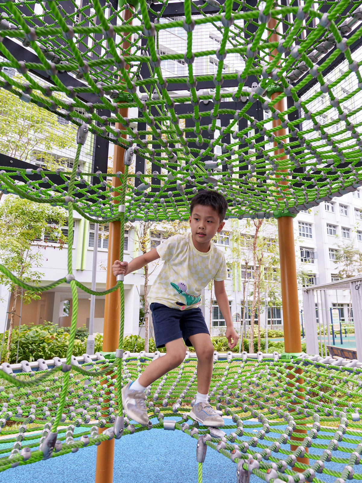 Boy climbing inside a Berliner Tower rope structure at the playground, engaging in adventurous and active outdoor play.