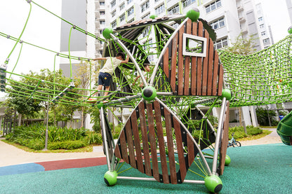 A boy crossing a cargo net bridge between two Berliner Treehouses, enjoying an exciting outdoor adventure.