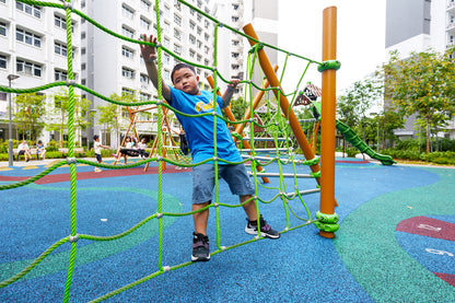 Boy climbing a rope net at Yishun Melody Spring playground, engaging in an exciting and challenging outdoor activity.