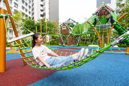 Girl relaxing on a hammock-style rope swing, gently swinging and enjoying her time at the playground.