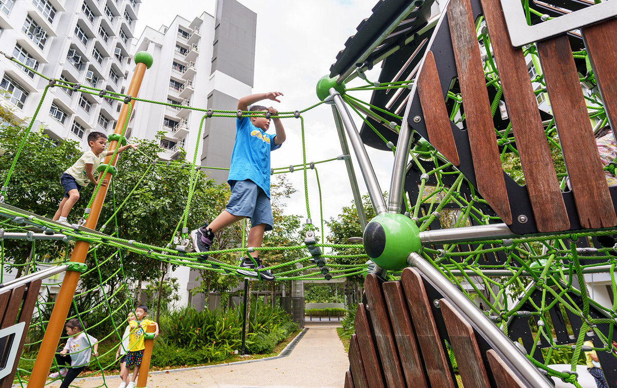 Boys crossing a cargo net bridge between two Berliner Treehouses, enjoying an exciting outdoor adventure.