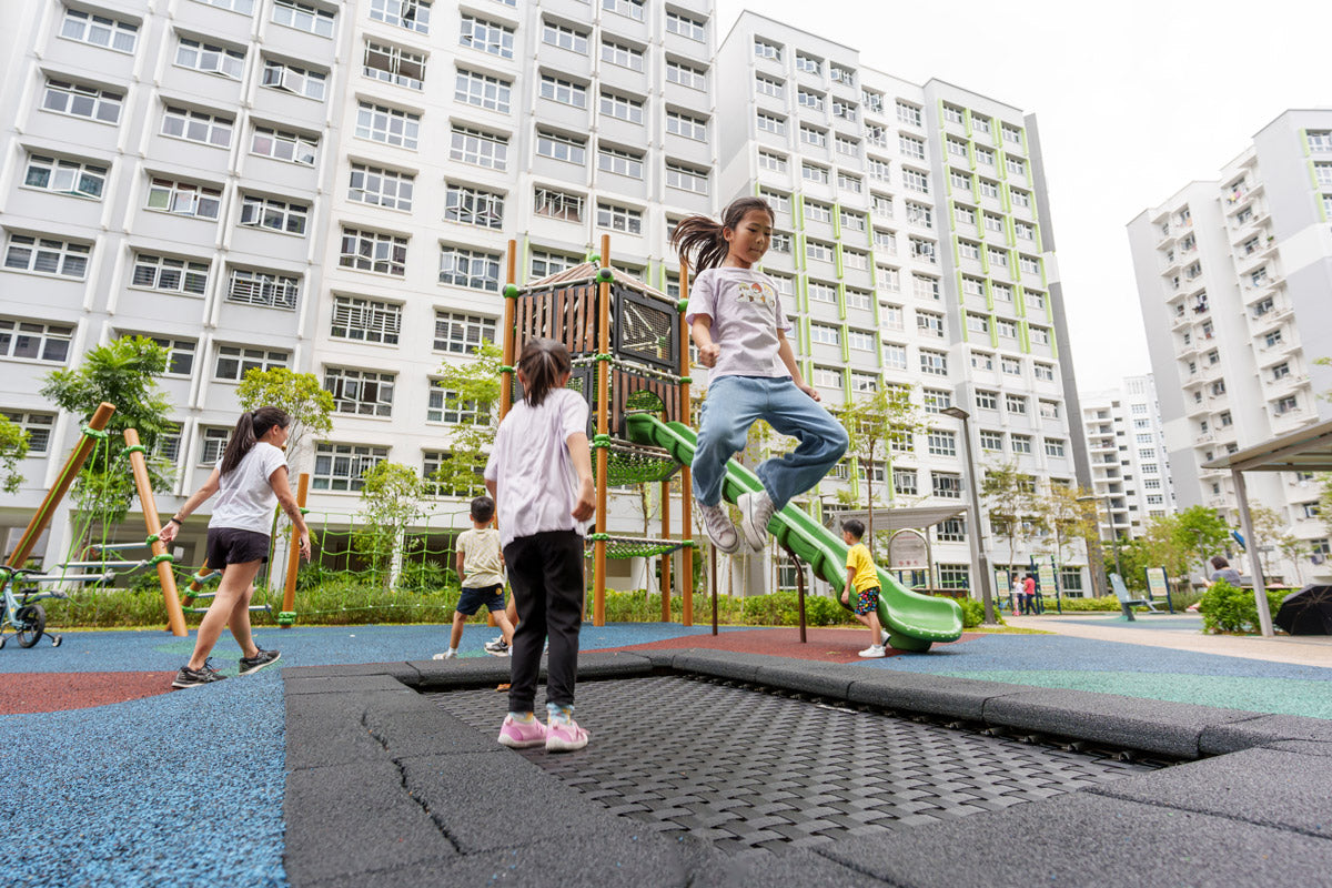 Girls jumping on a trampoline at Yishun Melody Spring playground, enjoying active fun and outdoor play.