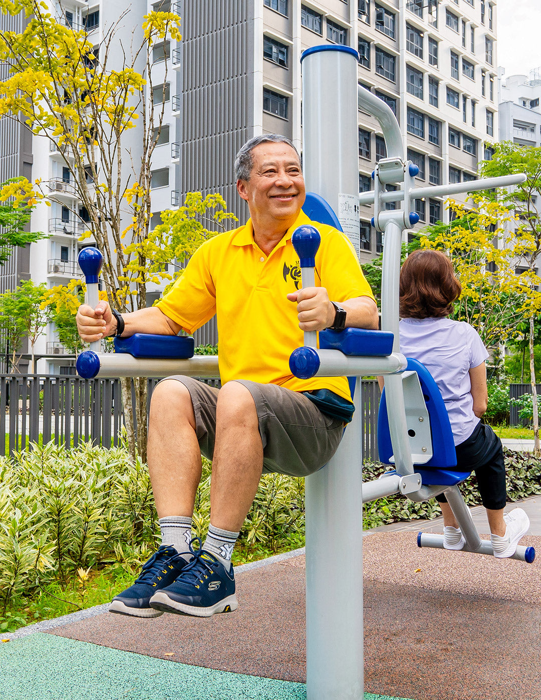 An elderly enjoying his workout on fitness equipment, smiling and keeping fit through training his chest, back, arm and abdominal muscles using the fitness corner machines.