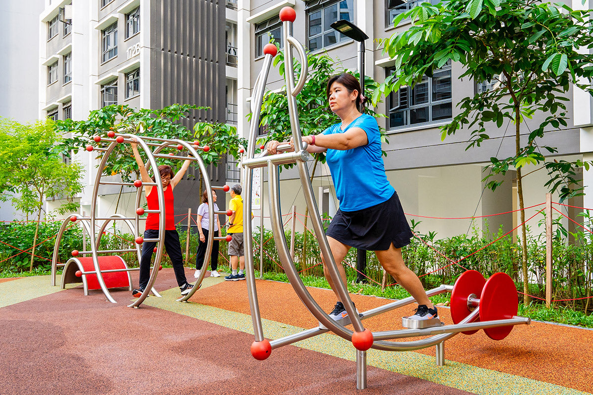 Woman using Stilum elliptical machine at a playground, promoting health, fitness, and an active lifestyle.