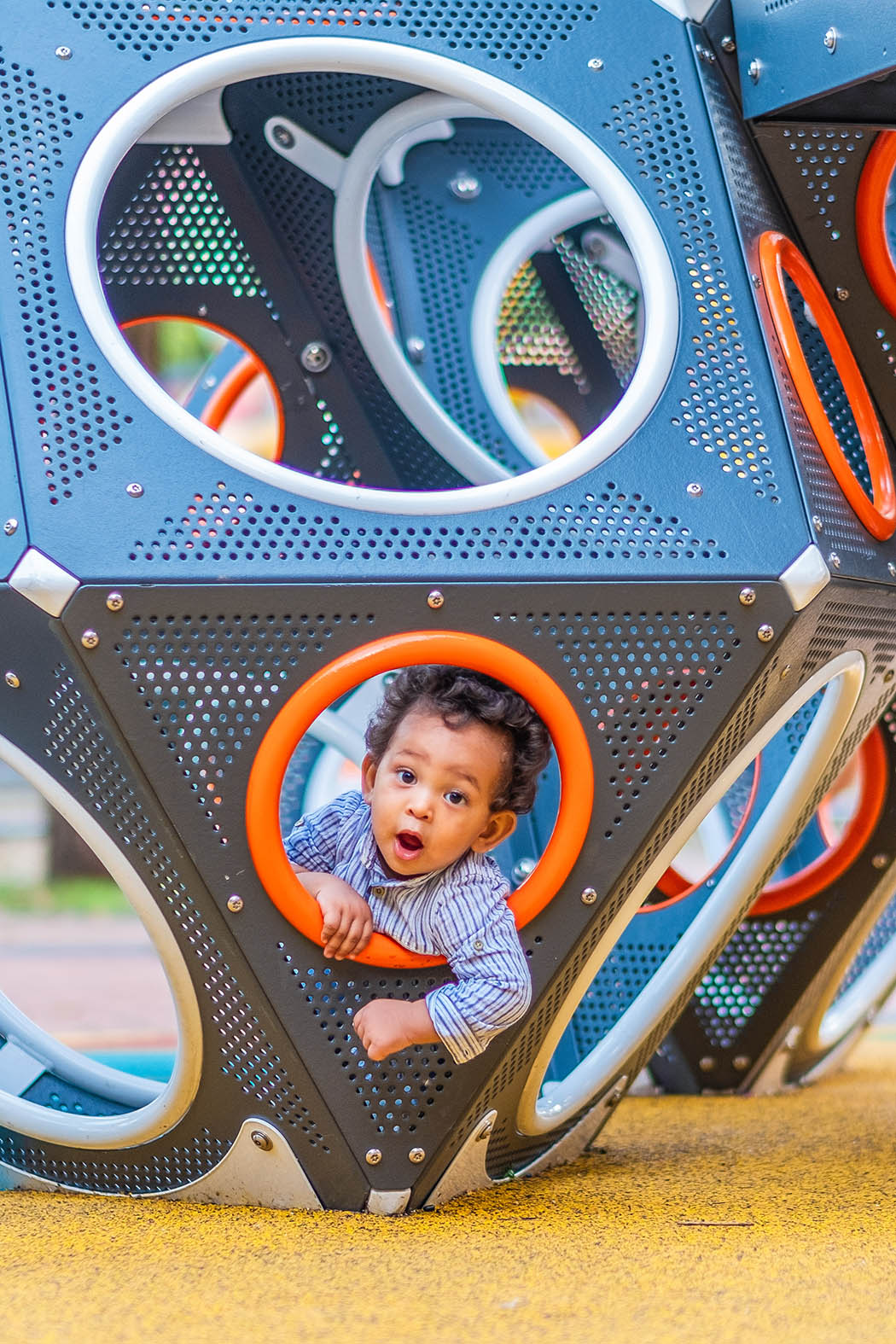 Boy joyfully playing in the Playworld PlayCube playground, curiously peeking his head out.