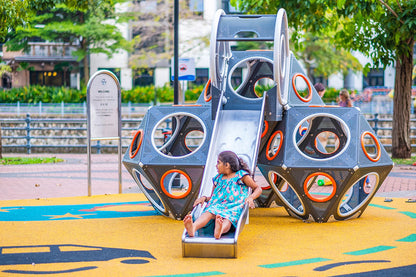 Girl joyfully sliding down the Playworld PlayCube slide, smiling and enjoying the moment.