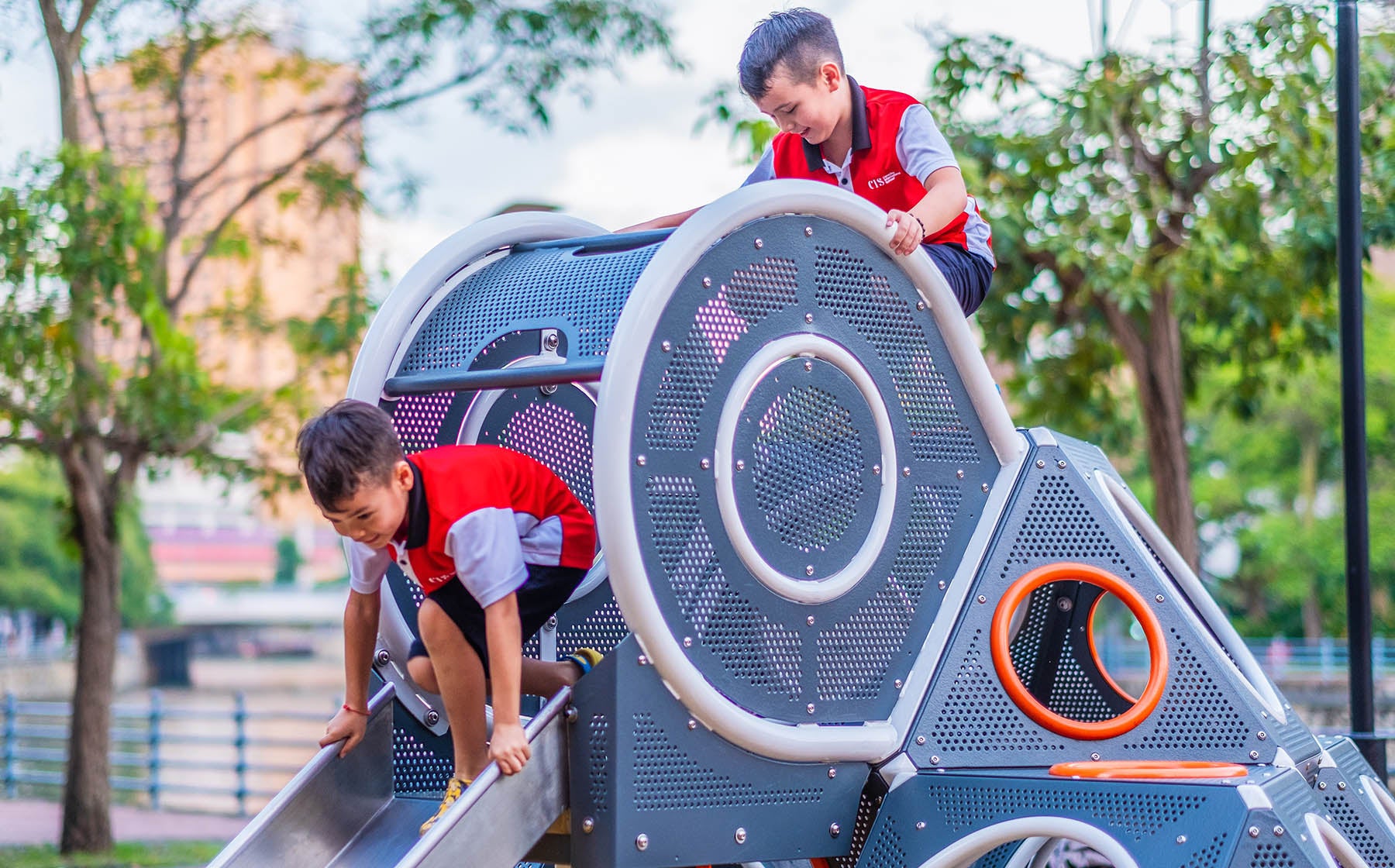 Children joyfully sliding down the Playworld PlayCube slide, smiling and enjoying their playtime.