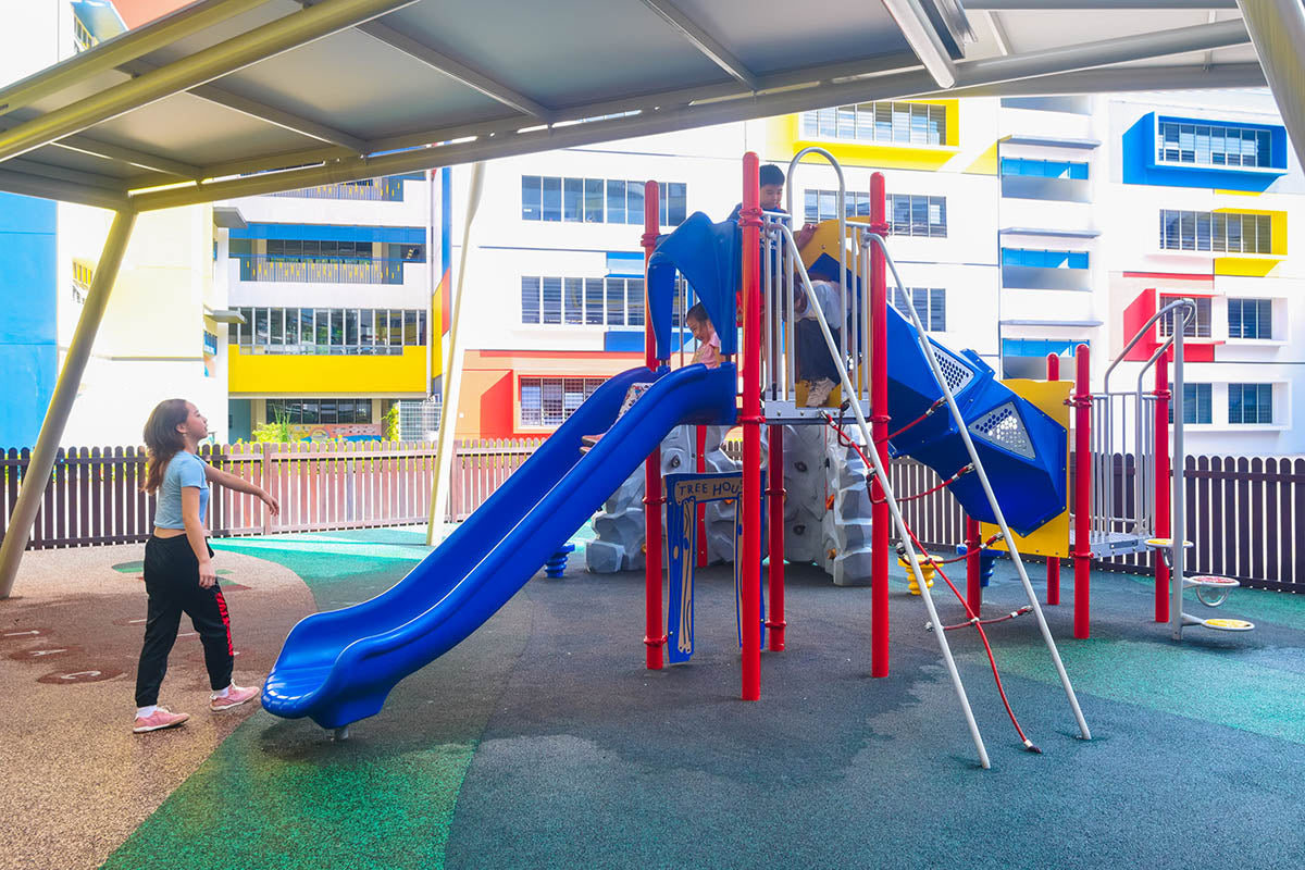 Children eagerly wait in line for the Playworld playground slide, excited for fun and outdoor adventure.