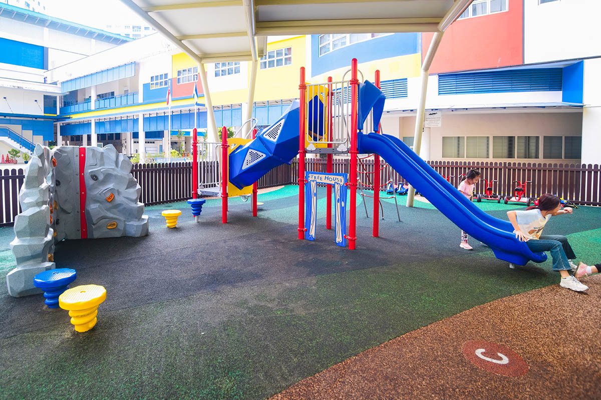 Girls sliding down the shaded Playworld playground slide, enjoying the fun and excitement of outdoor play.