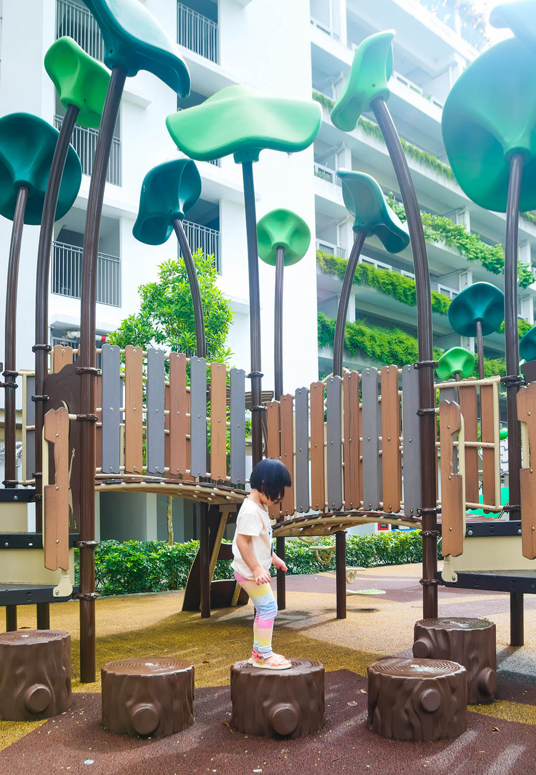 Child balancing on stump-like stepping stones in a Playworld playground, designed for fun and improving coordination skills.