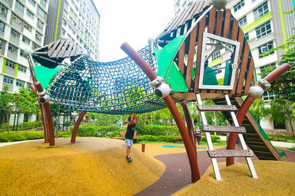 A boy is playing on the Berliner playground climbing net, gripping the ropes and having fun as he climbs.