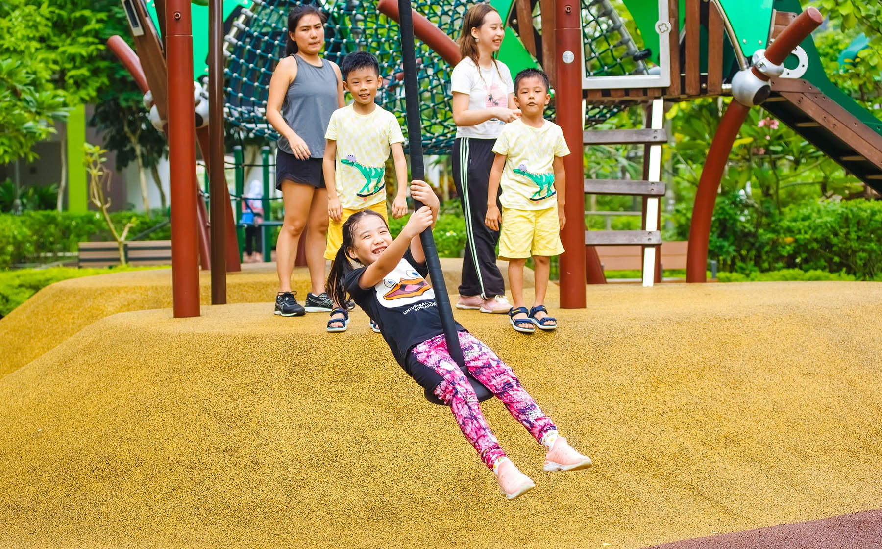 A child joyfully gliding on a zipline at a vibrant playground, surrounded by lush greenery and colorful play structures.