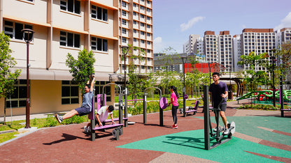 Outdoor fitness corner with elliptical trainer , turnable , a push-up bench, and rubberized flooring, surrounded by greenery.